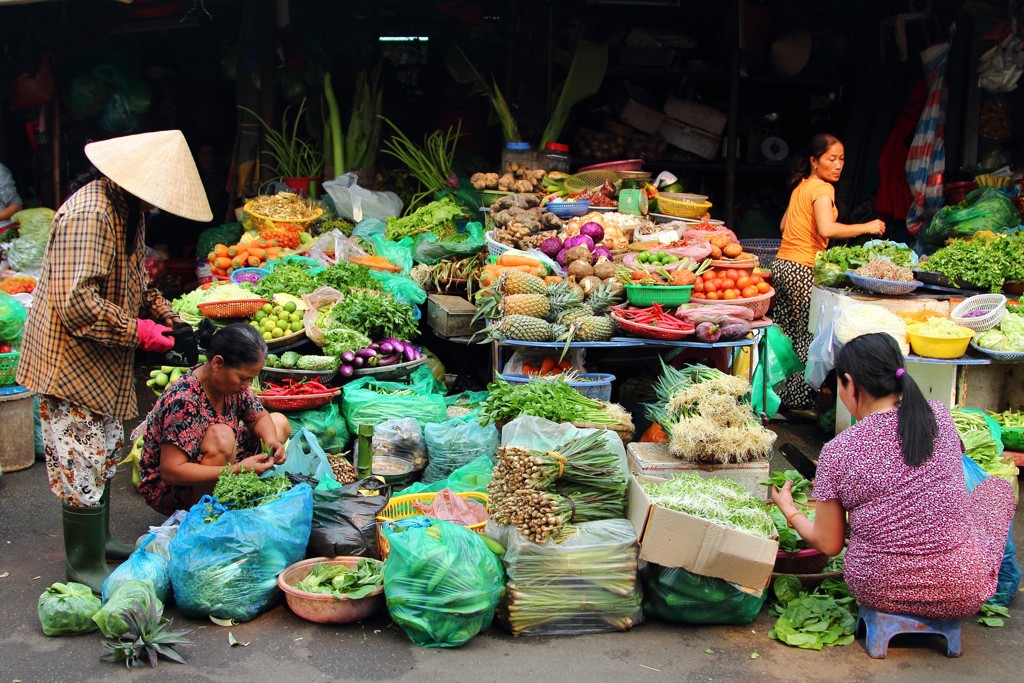 Groentemarkt in Vietnam met kramen vol verse kruiden, fruit en groenten tijdens een groepsrondreis.