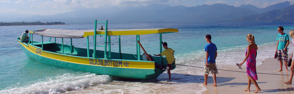 Glasbodemboot aan het strand op de Kleine Sunda Eilanden in Indonesië, met bergen op de achtergrond.