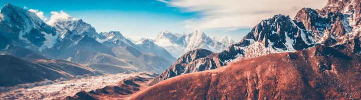 Turquoise bergmeer met besneeuwde Himalaya-toppen in Nepal onder een heldere blauwe lucht.