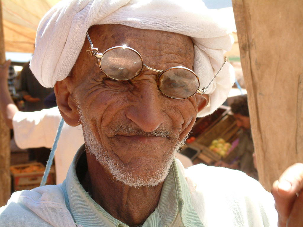 Portret van een man met witte tulband en bril op een markt in Marokko.