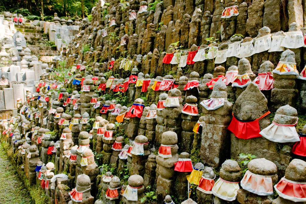 Rijen Jizo-beeldjes met rode slabbetjes bij een Japanse tempel, passend bij een familiereis Japan.