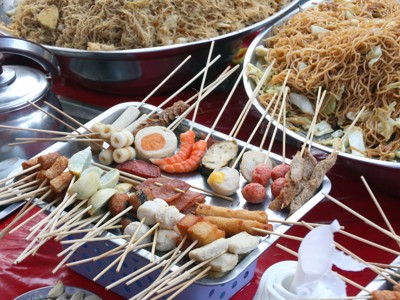 Streetfood in Myanmar met satéspiesjes, noedels en snacks op een marktkraam.