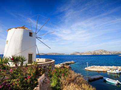 Witte windmolen aan zee bij een kleine haven op Paros, Griekenland.