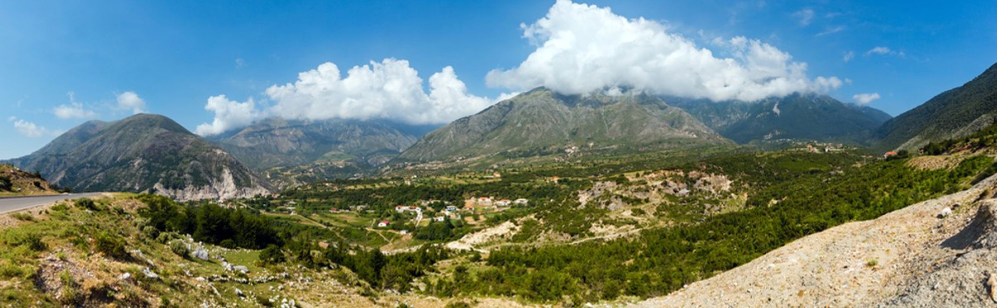 Panoramisch uitzicht op een groene vallei met bergen en wolken in Albanië.