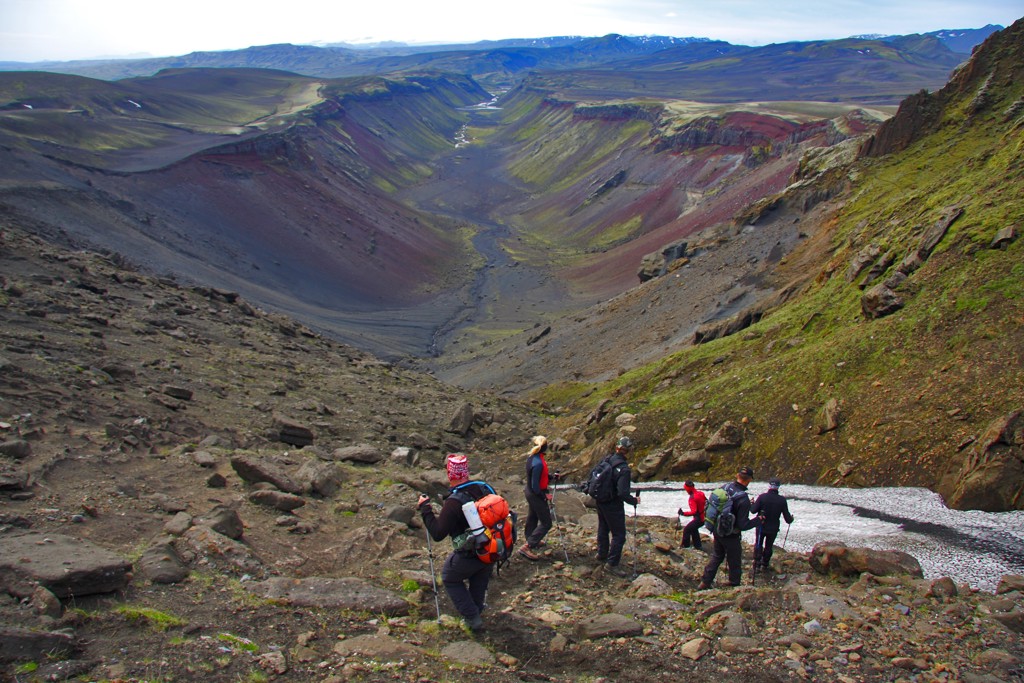Wandelaars dalen af in een ruige bergvallei langs de Laugavegur Trail in IJsland.