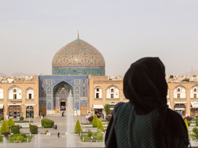 Vrouw kijkt uit op de Imam-moskee met blauwe koepel op het Naqsh-e Jahan-plein in Isfahan, Iran.