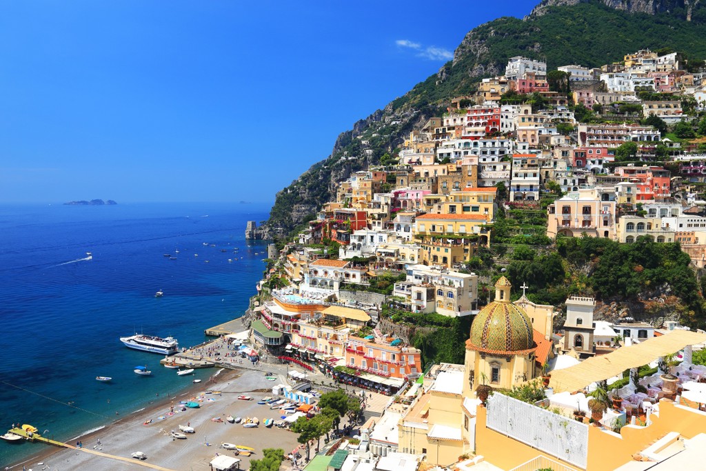 Uitzicht op Positano aan de Amalfikust met kleurrijke huizen tegen de kliffen en het strand aan zee.