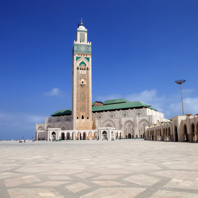 Hassan II-moskee in Casablanca, Marokko, met hoge minaret en groot plein onder een blauwe lucht.