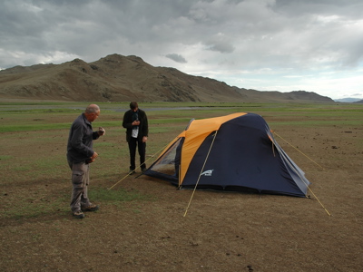 Kamperen met tent in de Mongoolse steppe, met bergen op de achtergrond.