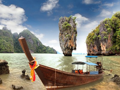 Longtailboot in de baai van Phang Nga, Thailand, met kalksteenrotsen en groene heuvels op de achtergrond.