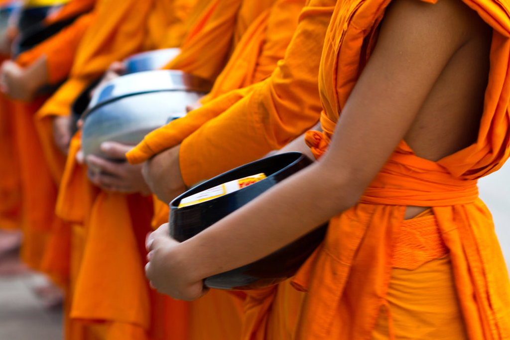 Boeddhistische monniken in oranje gewaden met offerkommen tijdens een groepsrondreis door Thailand Noord en Zuid.