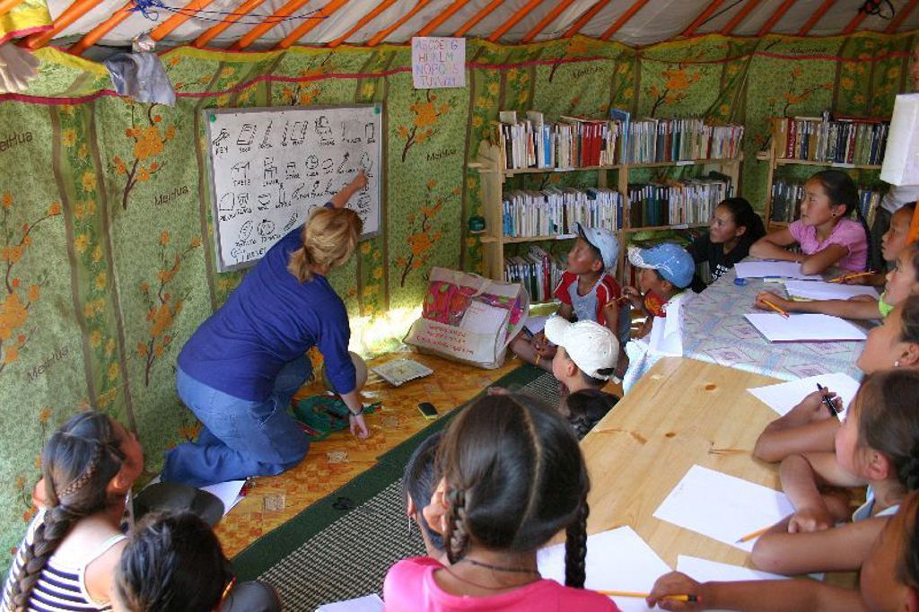 Les in een Mongoolse ger, met kinderen rond een tafel en een docent bij het bord.