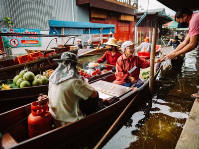 Drijvende markt in Thailand met verkopers in boten die groente en fruit verkopen via het kanaal.