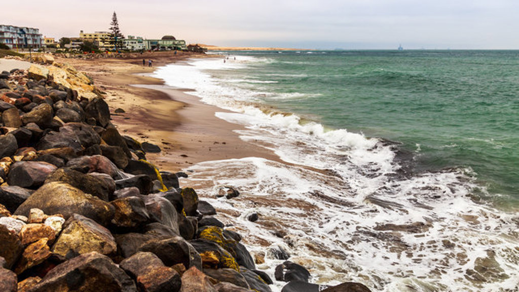 Kustlijn bij Swakopmund met rotsen, zandstrand en golven aan de Atlantische Oceaan.