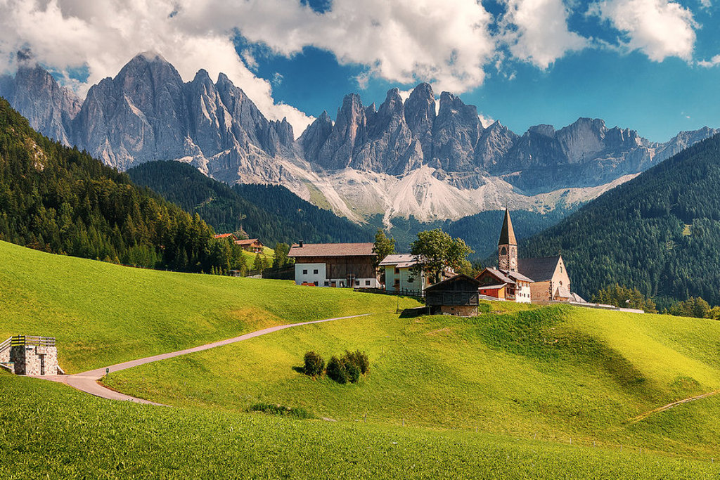 Groene alpenweide met dorp en kerkje, met ruige bergtoppen op de achtergrond tijdens groepsrondreis Centraal Europa.