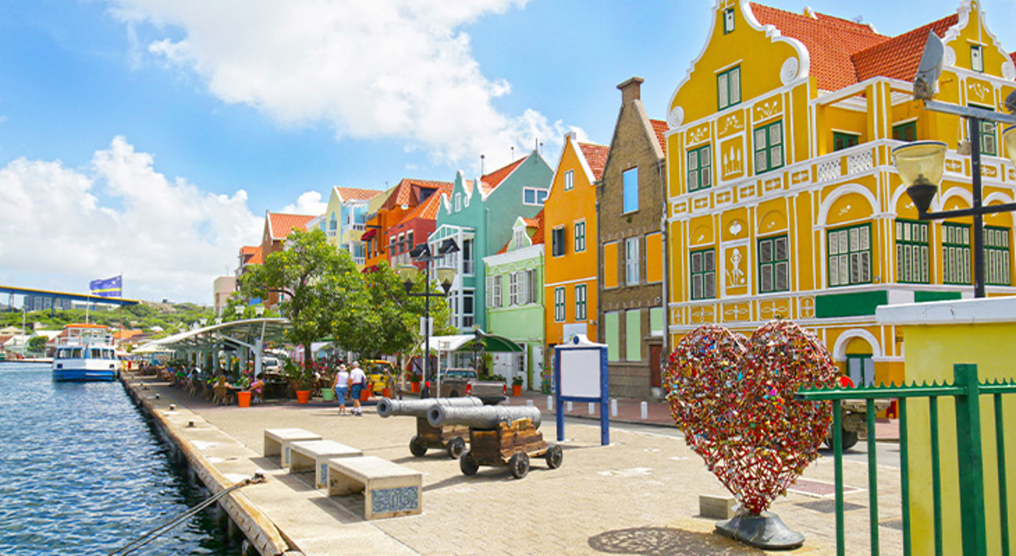 Kleurrijke gevels en promenade aan de Handelskade in Willemstad, Curaçao, met haven en kunsthart.