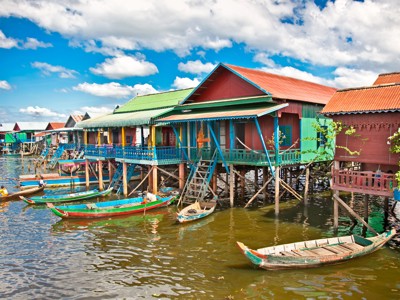 Kleurrijke paalwoningen en houten boten op het water bij het drijvende dorp Kampong Phluk, Cambodja.