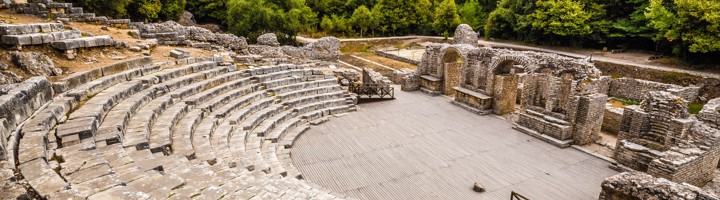 Oud Romeins amfitheater in Butrint, Albanië, omringd door groene bossen.