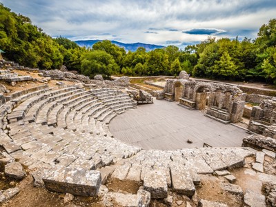 Oud Romeins amfitheater in Butrint, Albanië, omringd door groene bossen.