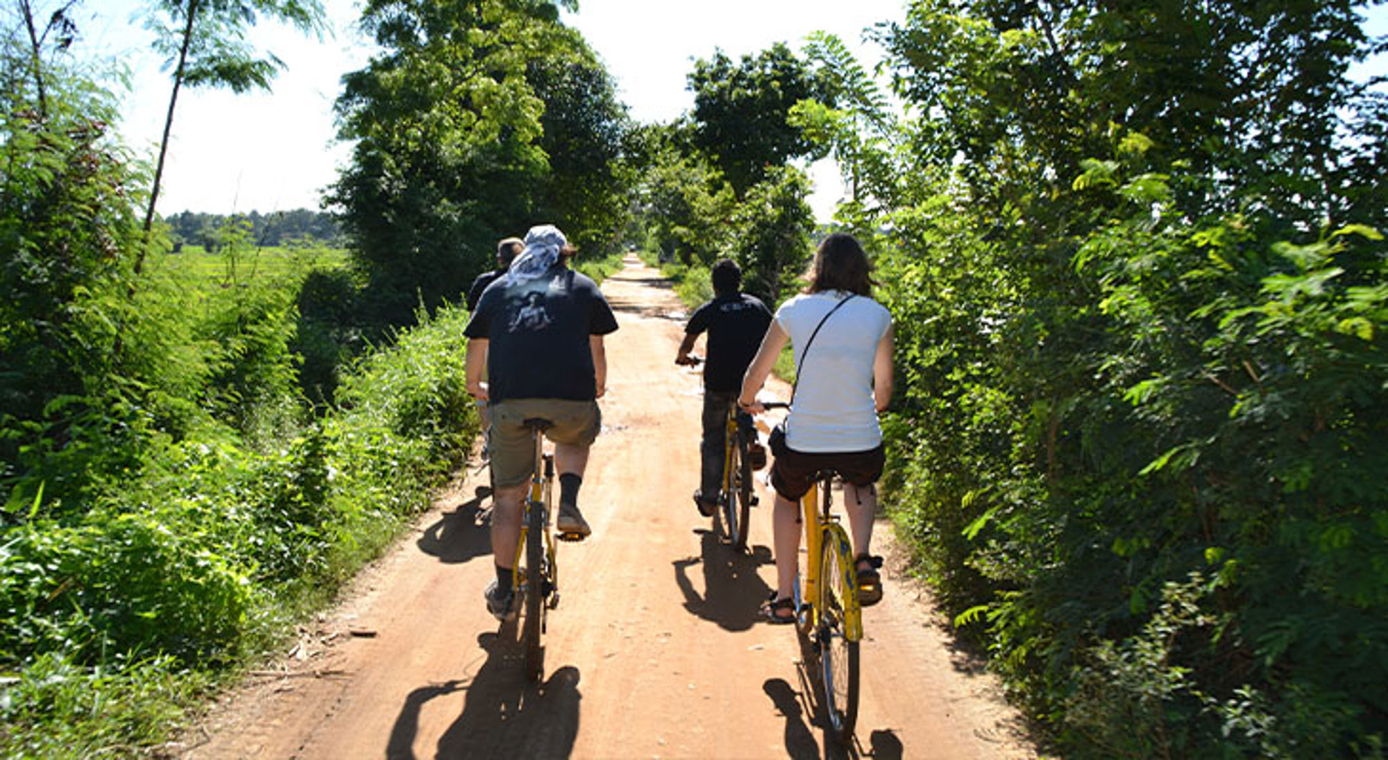 Polonnaruwa Sri Lanka Fietsers op een zonnige landweg omringd door groen tijdens een fietstocht.