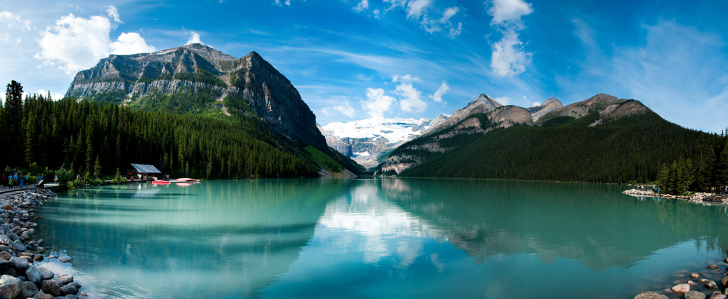 Turquoise bergmeer in de Canadese Rockies met dennenbossen en besneeuwde bergtoppen.