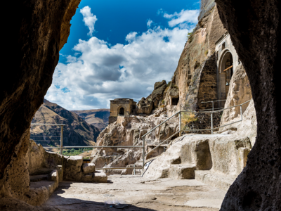 Uitzicht vanuit een grot op het rotsklooster Vardzia in Georgië, met trappen en uitgehouwen kamers.