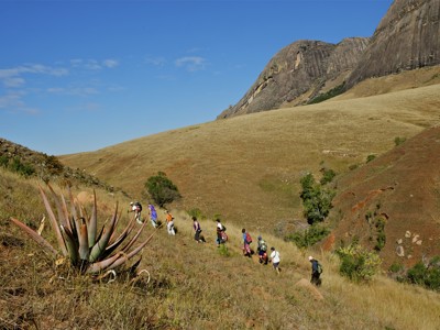 Wandelaars op bergpad in het Isalo Nationaal Park, Madagascar, met rotsformaties en savannelandschap.