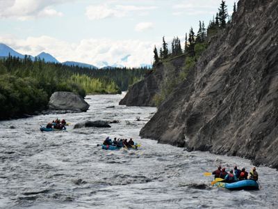 Raften op een wilde rivier in Alaska langs steile rotswanden en naaldbos.