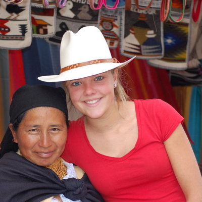 Reizigers poseren bij een marktkraam met kleurrijke textielwaren tijdens een familiereis in Ecuador.