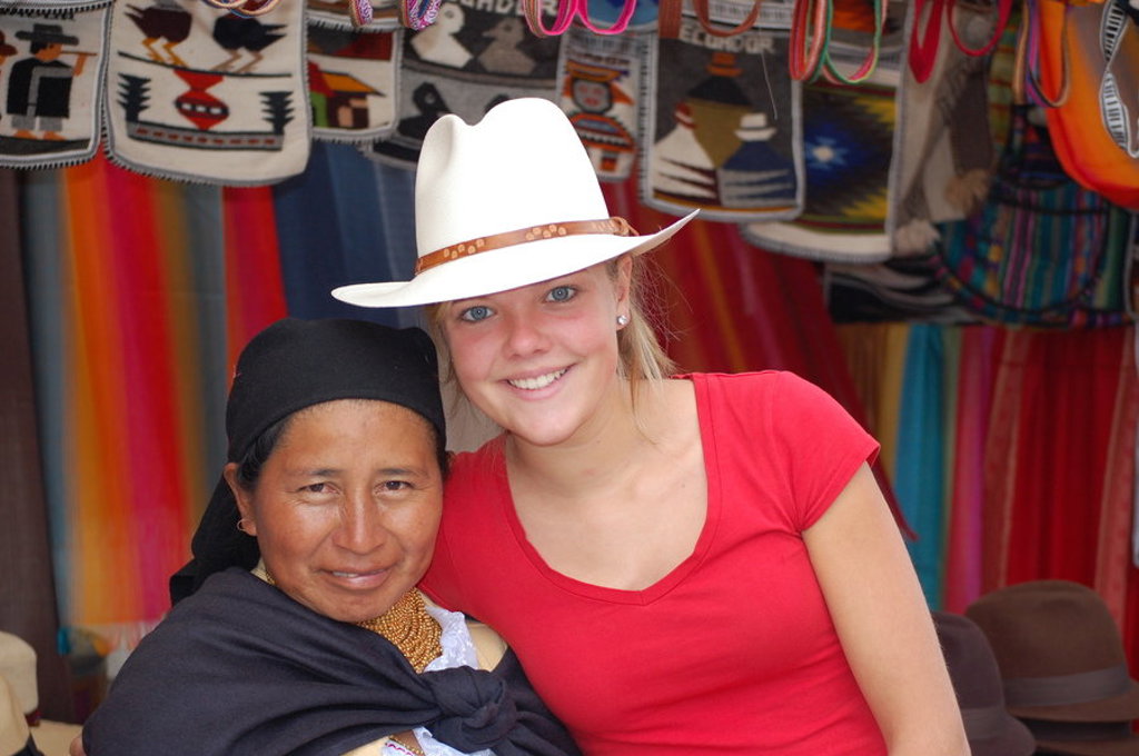 Reizigers poseren bij een marktkraam met kleurrijke textielwaren tijdens een familiereis in Ecuador.