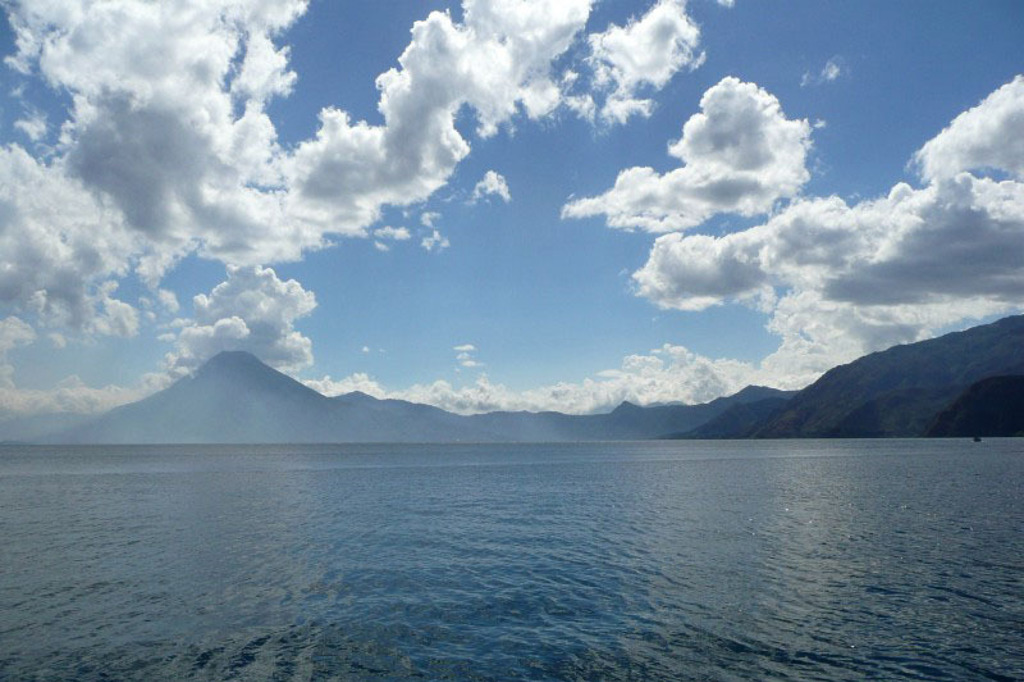 Uitzicht over het Atitlánmeer met vulkanen en wolkenlucht tijdens groepsrondreis Trans-Midden-Amerika in Guatemala.