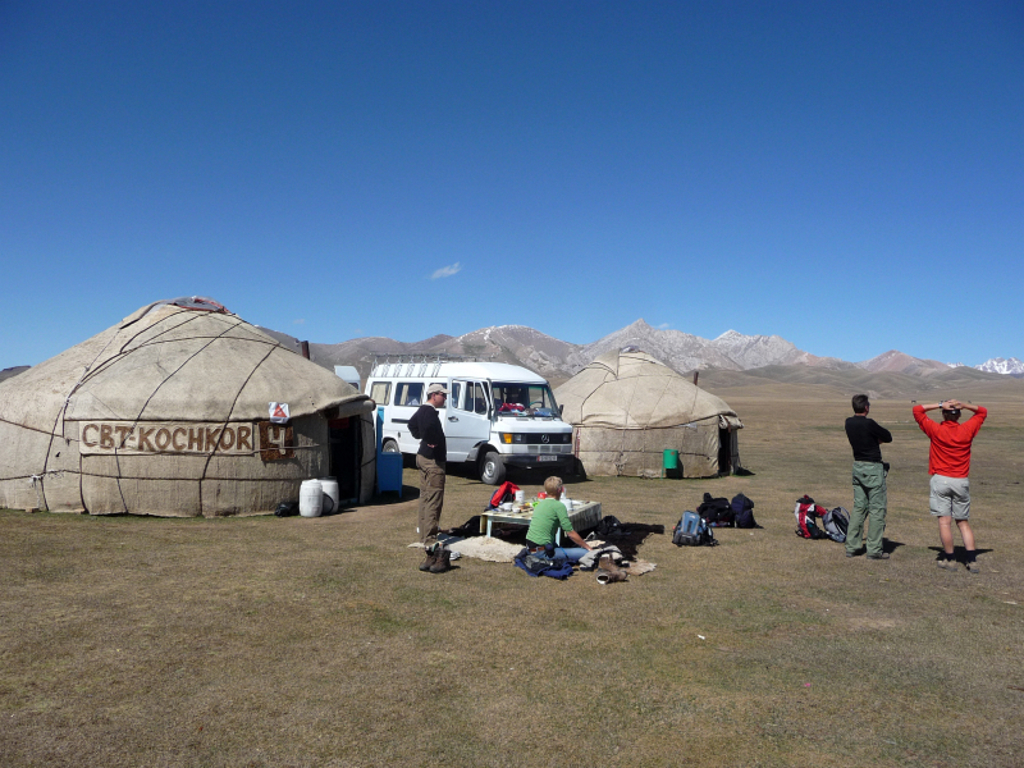 Wandelaars bij een yurtkamp in Kirgistan, met bergen op de achtergrond tijdens de groepsrondreis langs de Zijderoute.