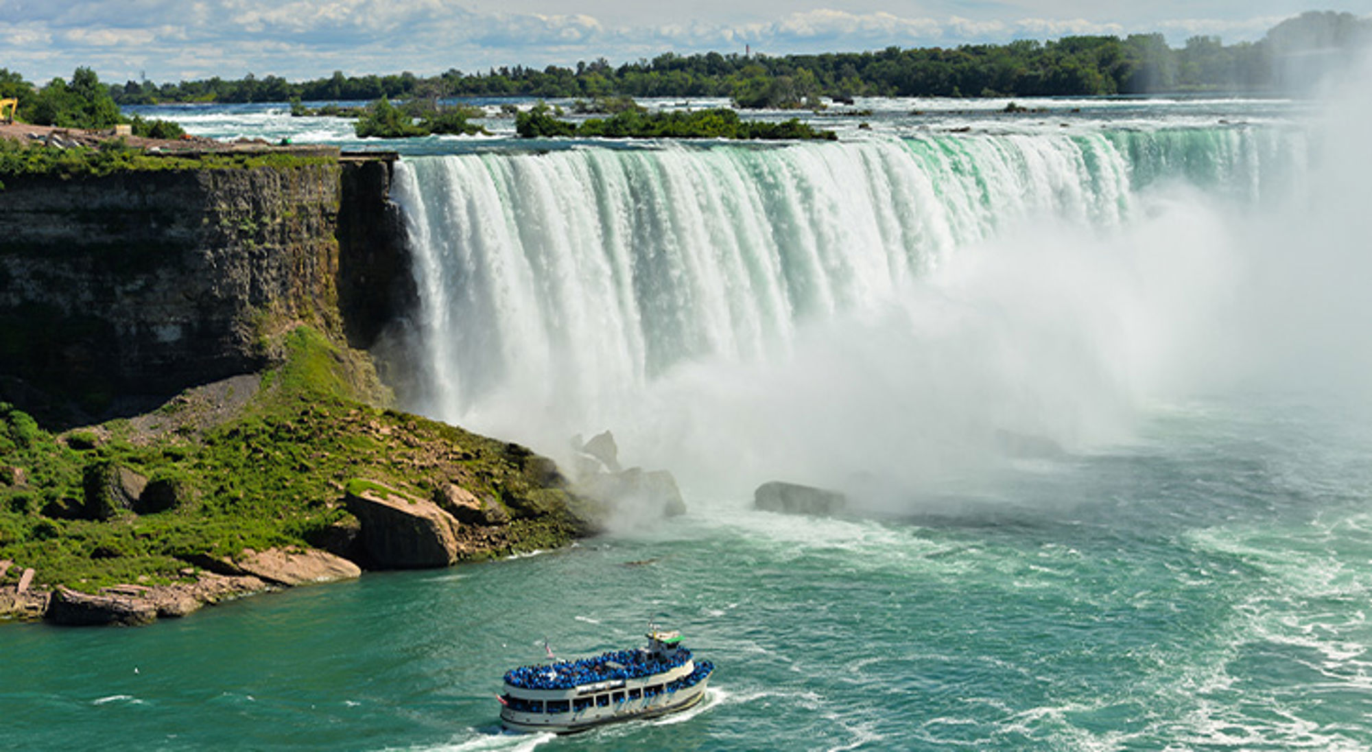 Niagara Falls Uitzicht op de Niagara Falls met nevel en een rondvaartboot op de rivier.