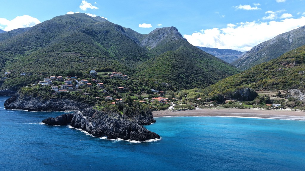 Kustdorp aan een baai met strand en groene bergen op Evia, Griekenland.