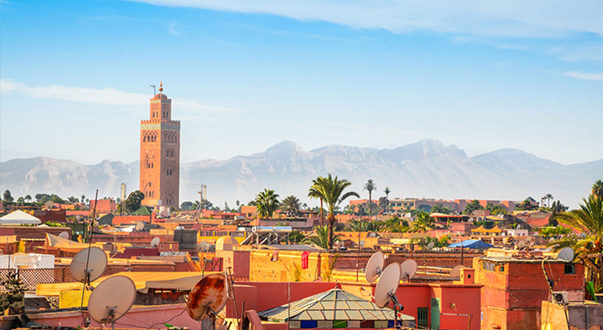 Marrakech Marokko Uitzicht over Marrakech met de Koutoubia-minaret, daken en palmbomen, met het Atlasgebergte op de achtergrond.
