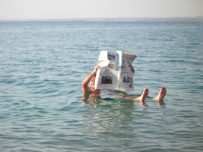 Persoon drijft in de Dode Zee en leest een krant tijdens route Jordanië en Israël, 13 dagen.