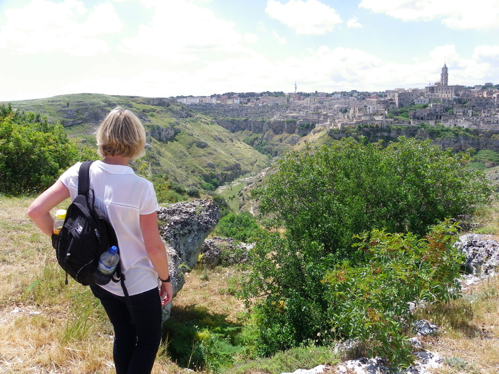 Wandelaar met rugzak kijkt uit over de kloof en het historische Matera in Puglia, Italië.