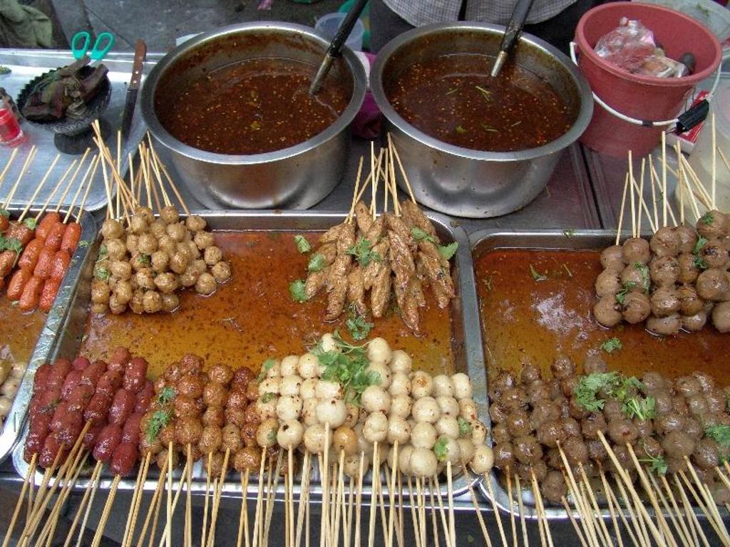 Thaise streetfoodkraam met spiesjes en gehaktballetjes in saus, op een markt tijdens de familiereis Thailand Chill & Adventure.