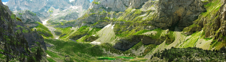 Groene vallei met bergtoppen en helder bergmeer in de Albanese Alpen.
