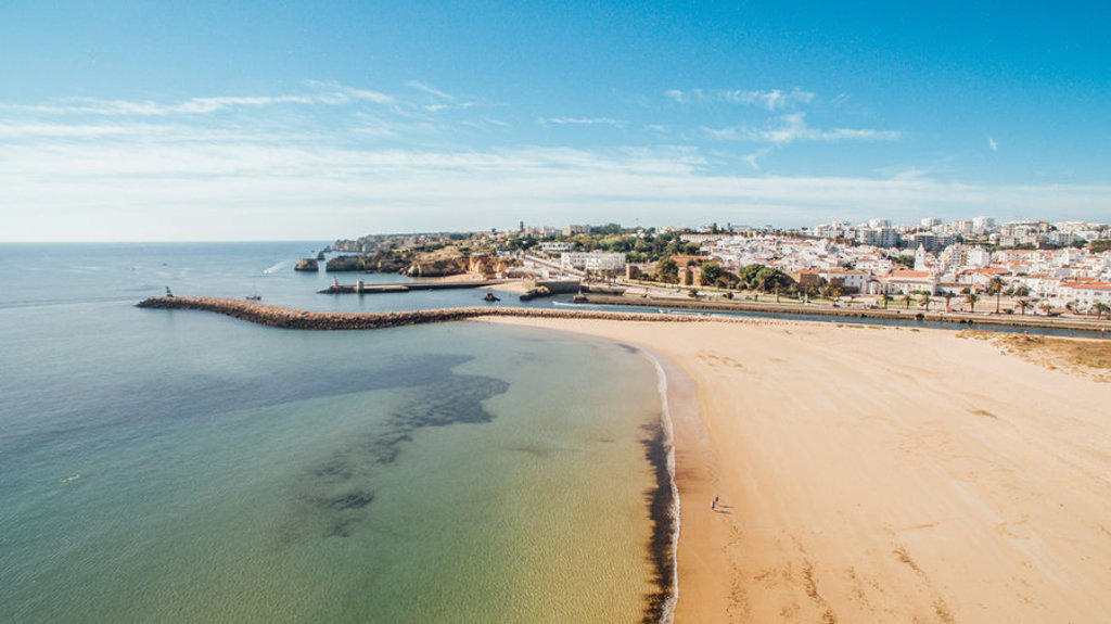Zandstrand en kustlijn bij Albufeira in Portugal, met uitzicht op de stad en de Atlantische Oceaan.