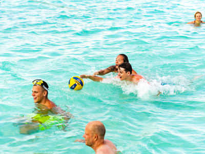 Gezin speelt met een bal in het heldere zeewater tijdens de familiereisroute in Mexico.
