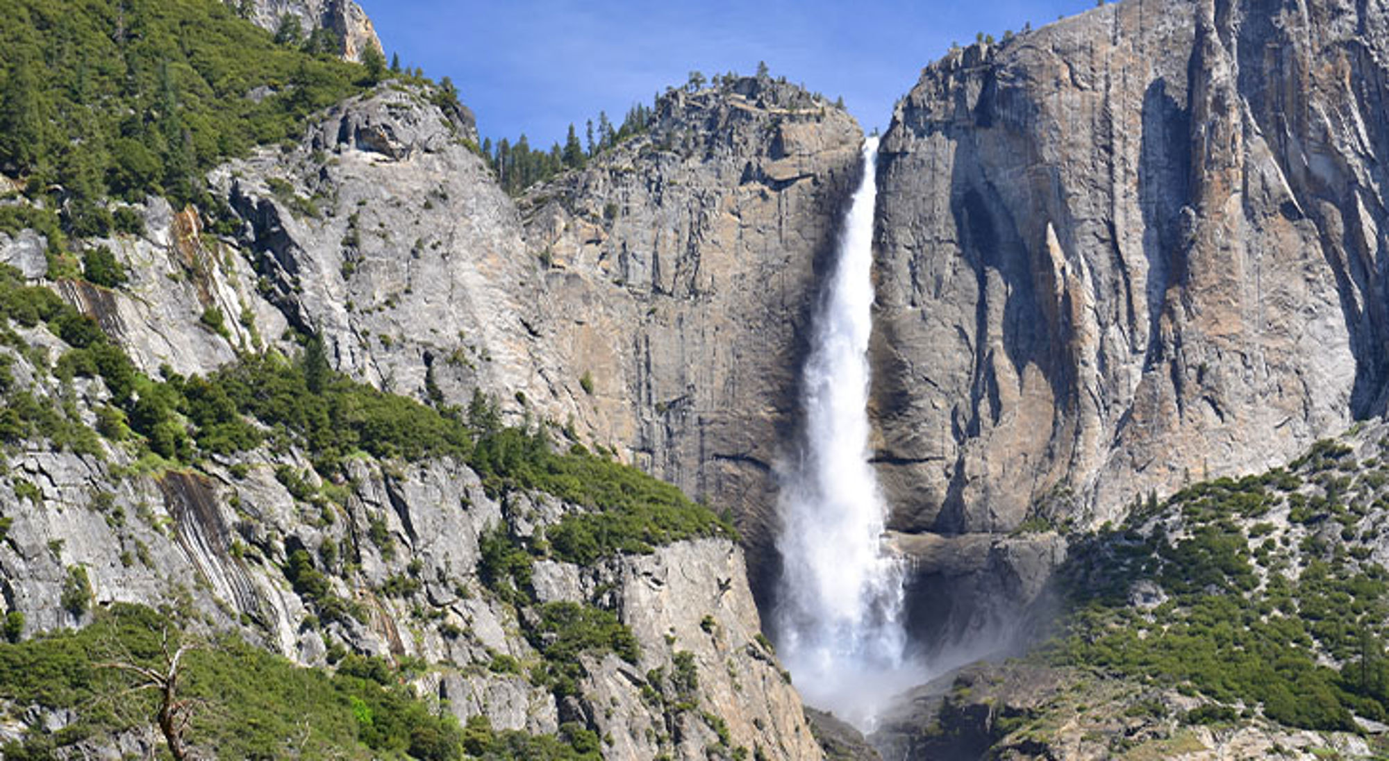 Waterval die langs steile rotswanden naar beneden stort in een berglandschap.