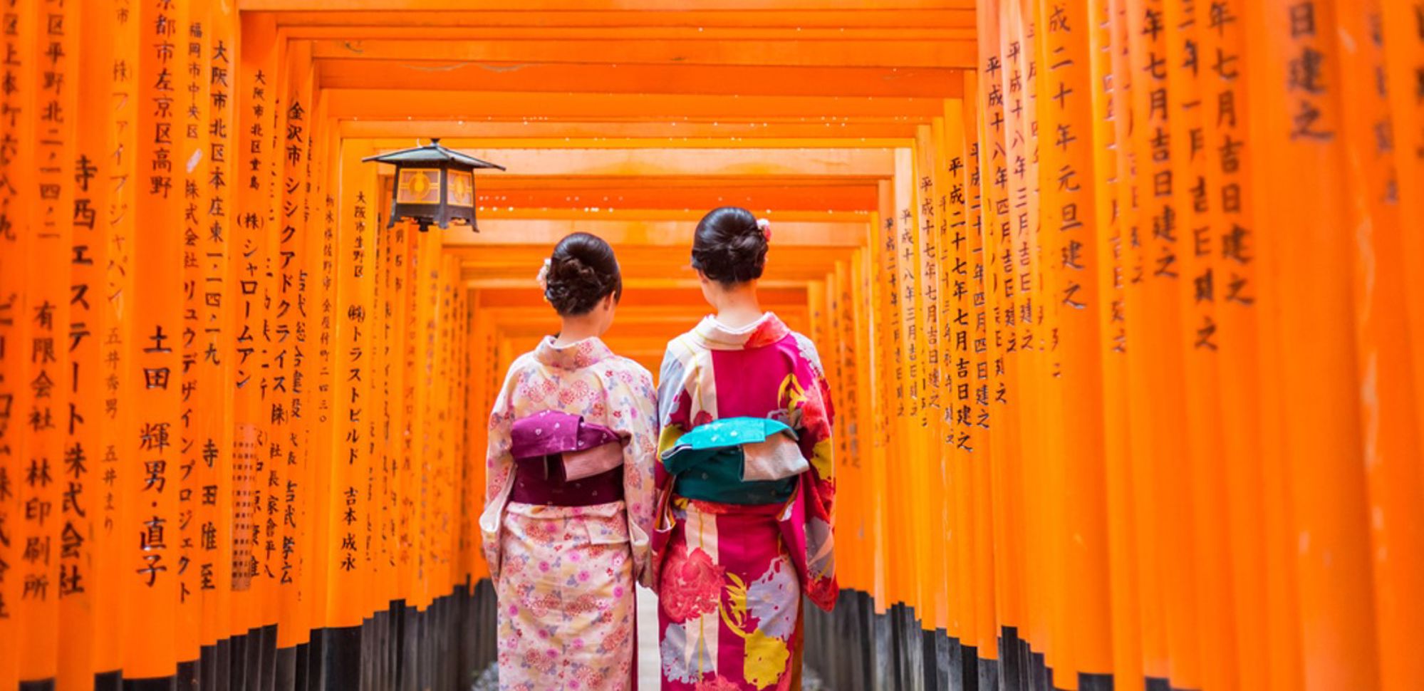 Twee vrouwen in kimono lopen door de rode torii-poorten van Fushimi Inari-taisha in Kyoto, Japan.