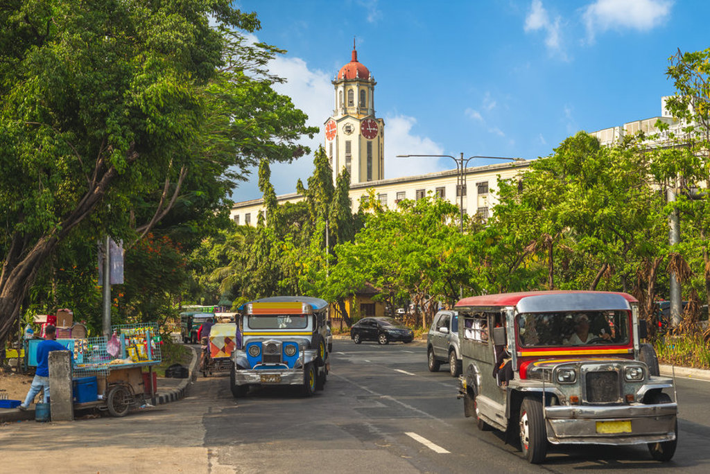 Jeepneys op straat in Manila met de klokkentoren van het stadhuis op de achtergrond, Filipijnen.