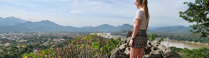Anna kijkt uit over de Mekongrivier en bergen tijdens haar 22-35ers reis door Thailand, Laos en Cambodja.