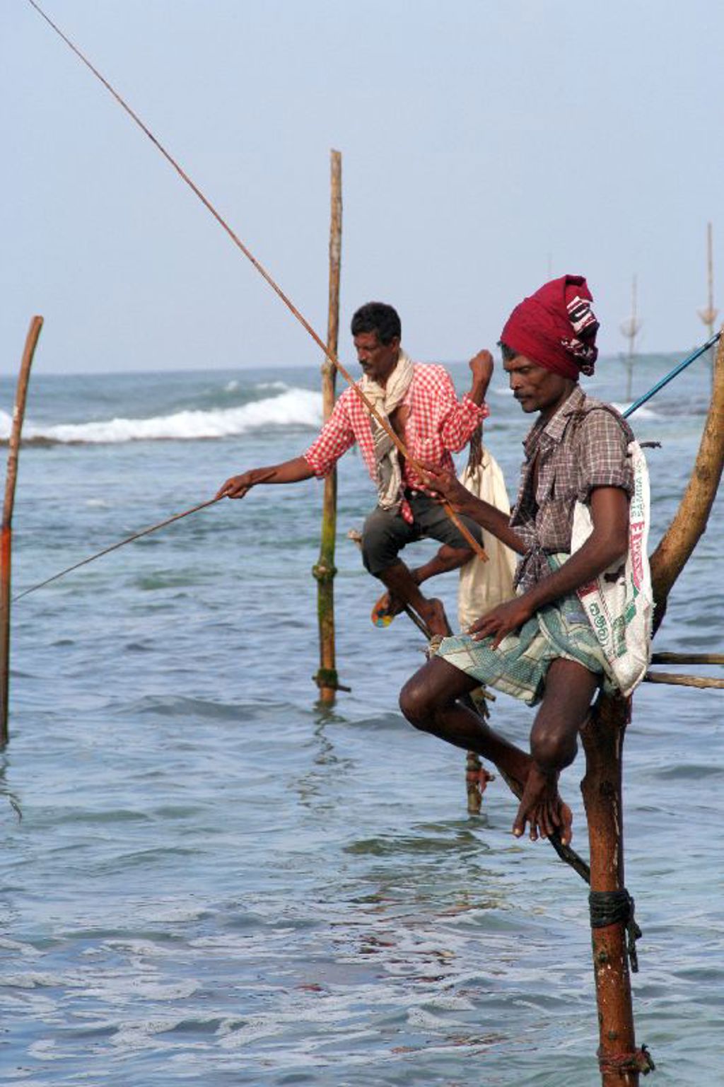 Stokvissers op palen in zee aan de kust van Sri Lanka tijdens een familiereis Sri Lanka en Malediven.