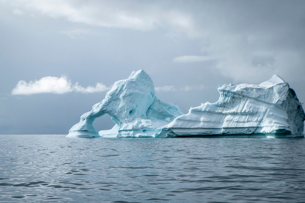 Grote ijsberg met natuurlijke boog drijvend op zee bij Spitsbergen, Groenland en IJsland-cruise.