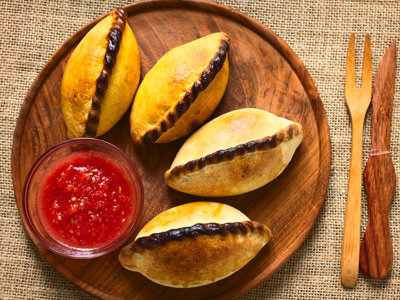 Empanadas met tomatensalsa op een houten bord, lokale specialiteit tijdens de route Bolivia en Chili.