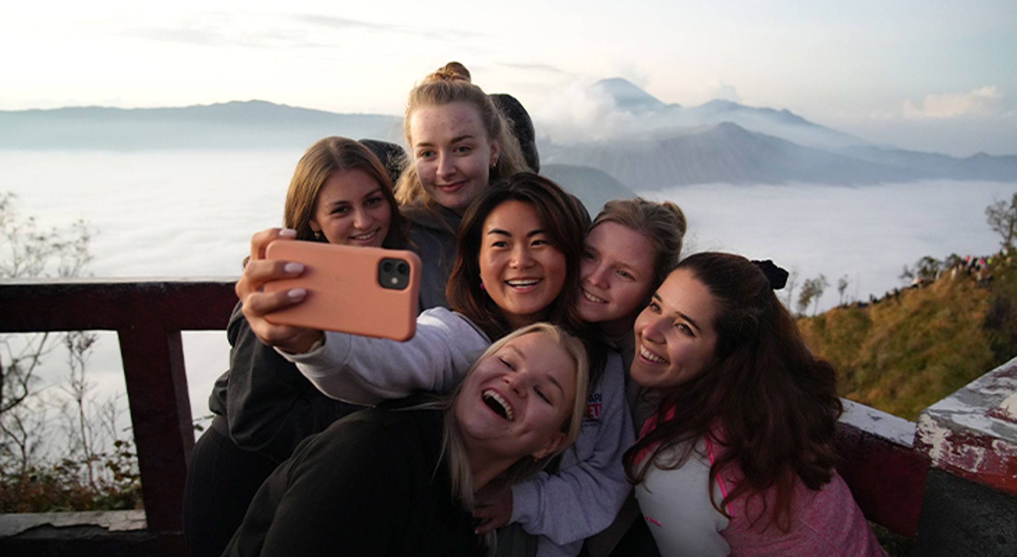 Bromo-vulkaan Java Vriendinnengroep maakt een selfie bij zonsopgang met uitzicht op bergen en mistige vallei.