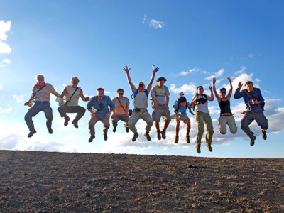 Reisgroep springt juichend in de lucht tijdens Route Nicaragua, 23 dagen, met blauwe lucht op de achtergrond.